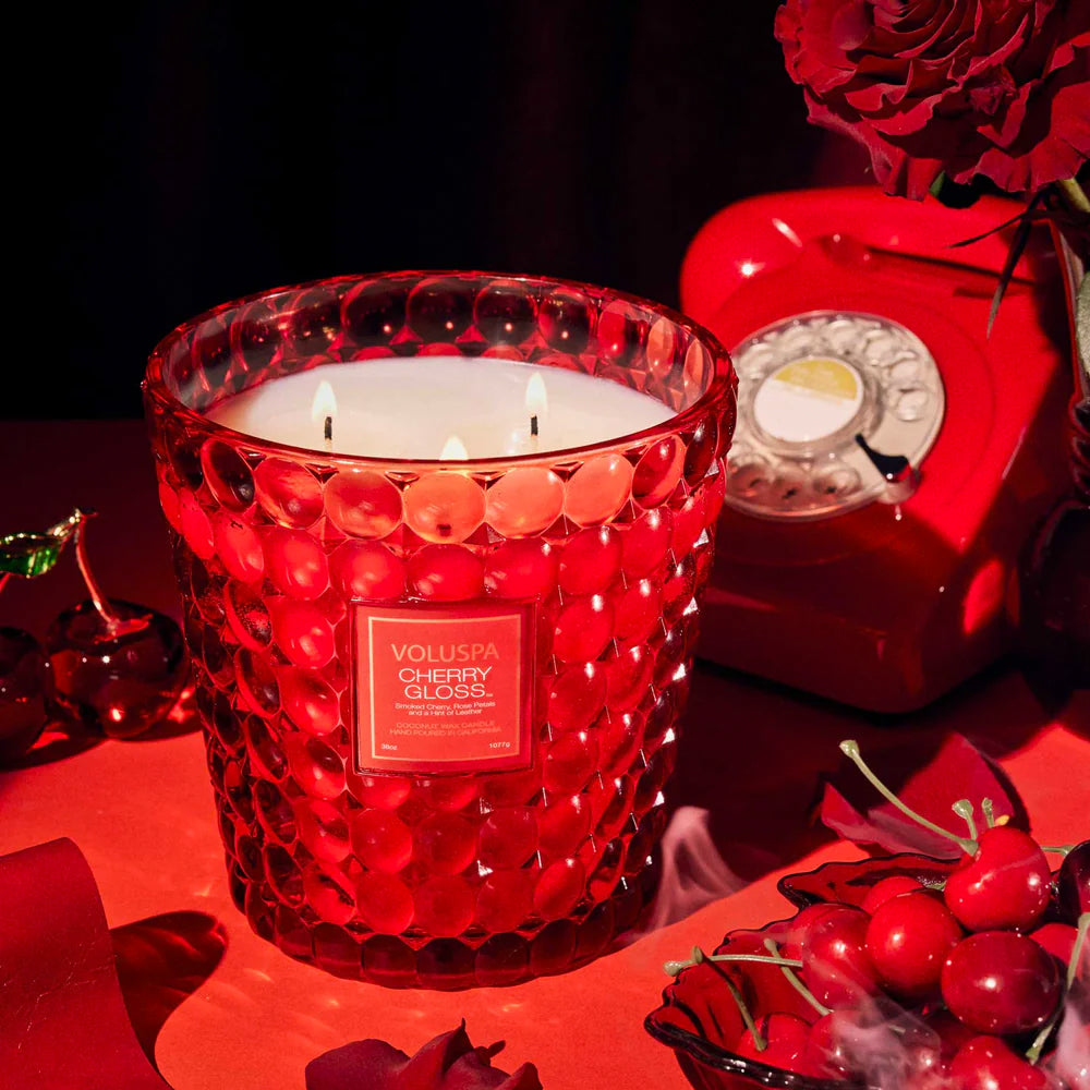 Grote Voluspa geurkaars in een roodkleurige glazen pot in de geur Cherry Gloss in een sfeerbeeld.